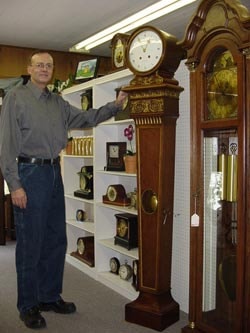 Peter Schryver standing next to a grandfather clock in his shop